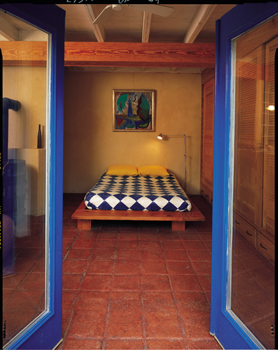 With its earthen tiles, glass doors, clay walls and rich wood, this bedrooms's décor is texture, not clutter.